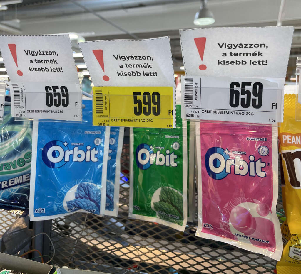 Three varieties of Orbit gum hanging on a store display. Each pack shows a different flavor: peppermint, spearmint, and bubblemint. Above them, signs indicate a price in forints and mention the product has become smaller.