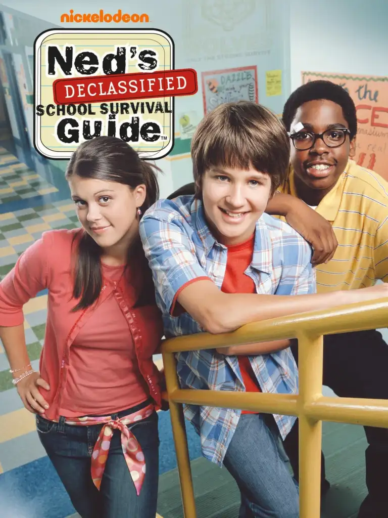 Three teenagers smile at the camera in a school hallway. A girl in a pink top stands on the left, a boy in a blue checkered shirt leans on a railing in the center, and another boy in glasses and a yellow shirt stands on the right. "Ned's Declassified" logo is above.