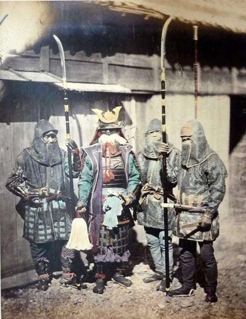 A vintage photograph shows four samurai in traditional armor, two holding naginatas. The central figure wears an ornate helmet with a crest. They stand in front of a wooden structure, displaying distinct historical attire.