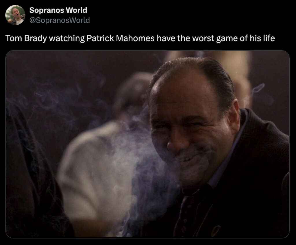 A man in a dimly lit setting, surrounded by smoke, is laughing and leaning forward. Text above reads, "Tom Brady watching Patrick Mahomes have the worst game of his life.