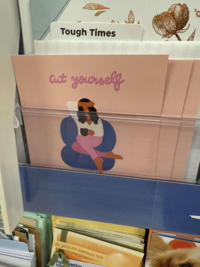 A card display features a card with an illustration of a person sitting in a blue chair, holding a book. The text "cut yourself" is on the card. Above, there is a label reading "Tough Times.