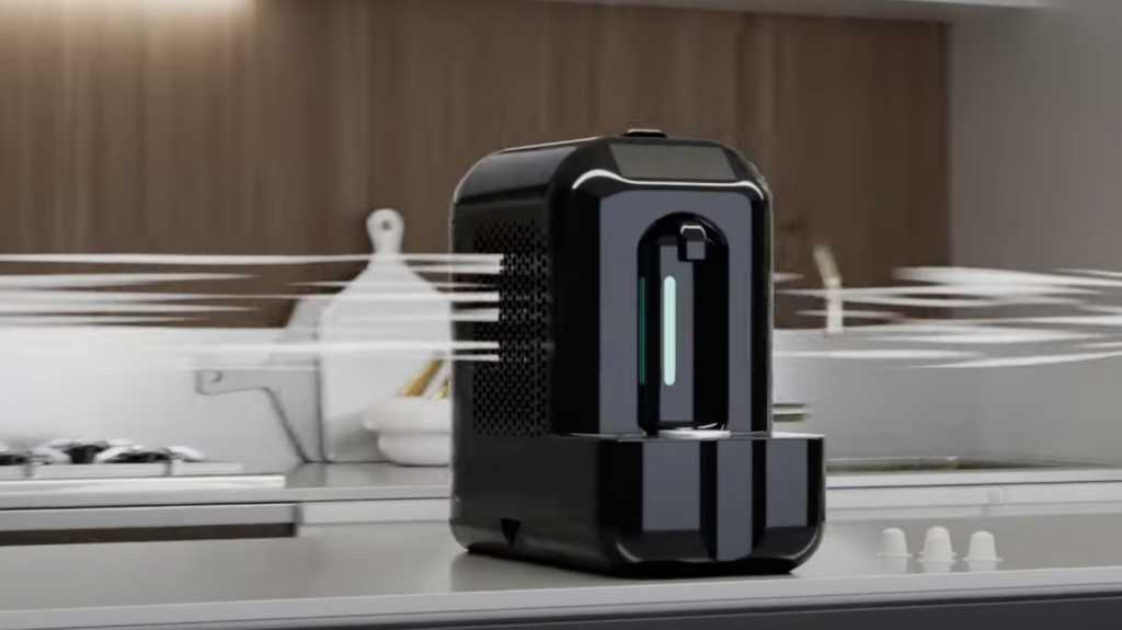 A sleek black air purifier is placed on a modern kitchen countertop, with swirling lines to indicate airflow. The background features a stovetop, wooden cabinets, and kitchen utensils.