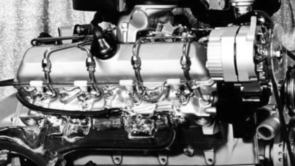 Black and white image of a mechanical engine showing detailed components, including wires, bolts, and housing. The metallic surface reflects light, highlighting the intricate design and engineering of the machinery.