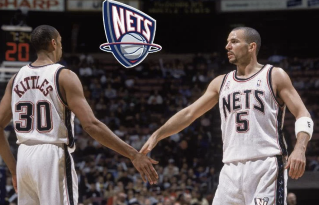 Two basketball players in white and blue Nets jerseys are on a court. Number 30 and number 5 are exchanging a hand gesture. A Nets logo is above them. The arena background is filled with spectators.