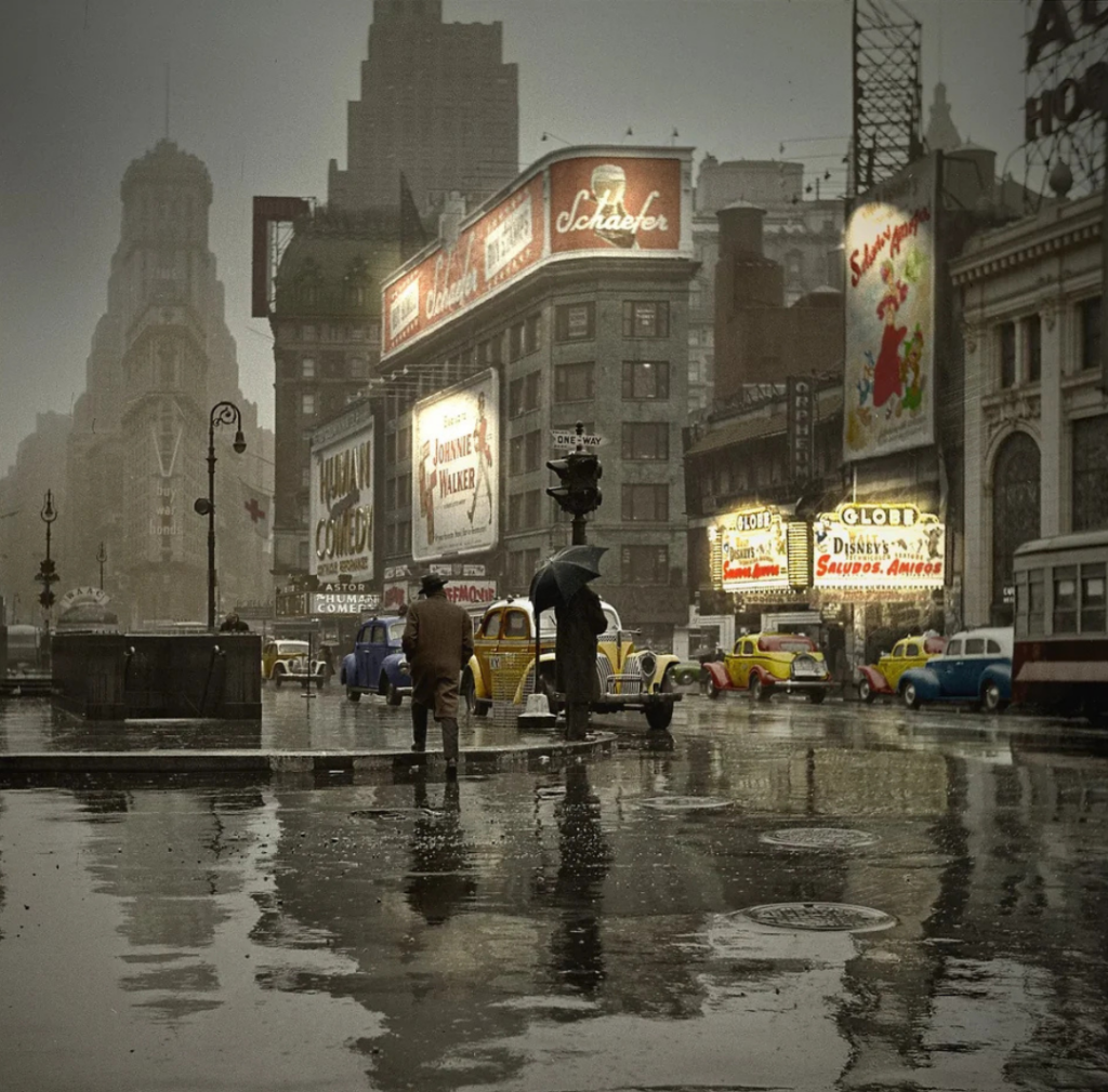 A vintage streetscape on a rainy day shows people walking under umbrellas. Brightly lit billboards and signs advertise various products. Classic cars drive through the wet streets, reflecting the colorful lights on the puddled ground.