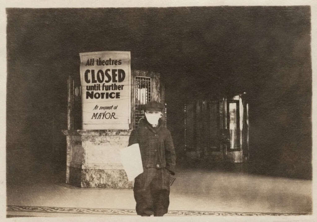 A person wearing a face mask and hat stands in front of a theater entrance. A sign behind them reads, "All theatres CLOSED until further NOTICE. At request of MAYOR." The scene is dimly lit, emphasizing the vintage setting.